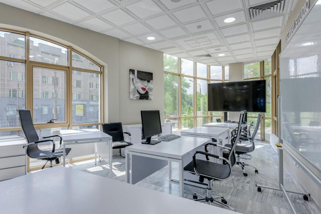 Contemporary minimalist office with glass windows and ergonomic chairs.