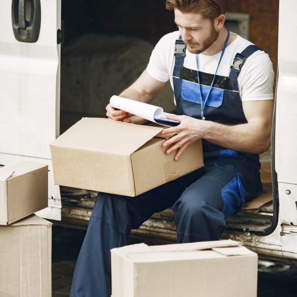 Man by the truck. Guy in a delivery uniform. Man with clipboard.